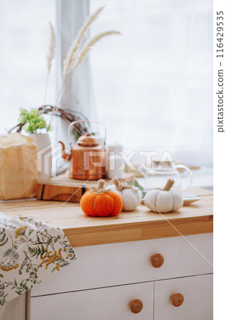 Bright kitchen with wooden furniture with kitchen utensils and three decorative pumpkins. Bright kitchen with wooden furniture with kitchen utensils and three decorative pumpkins. 116429535