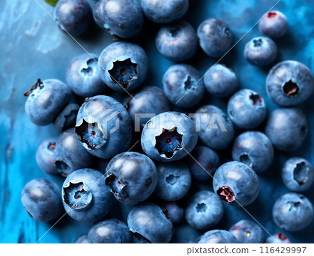 Collection of fresh blueberries neatly stacked on a vibrant blue table, creating a visually appealing display. 116429997