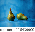Two ripe pears rest on top of a vibrant blue table, creating a simple yet striking still life composition. 116430000