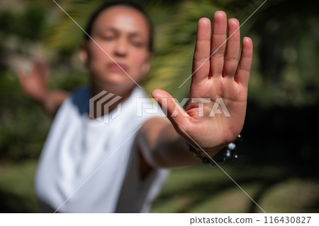 Woman practicing mindfulness and yoga outdoors with focus on hand gesture and blurred background 116430827