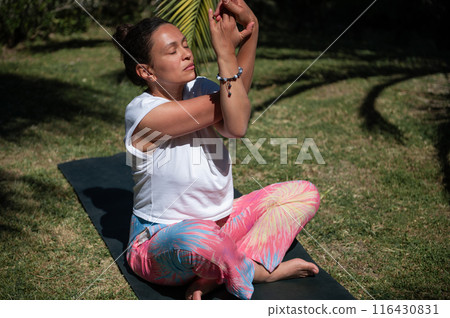 Woman practicing yoga outdoors on a sunny day with serene expression Woman practicing yoga outdoors on a sunny day with serene expression 116430831