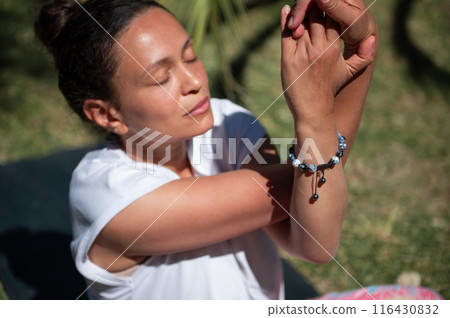 Woman practicing yoga outdoors in sunny weather, focusing on her breathing and mindfulness 116430832