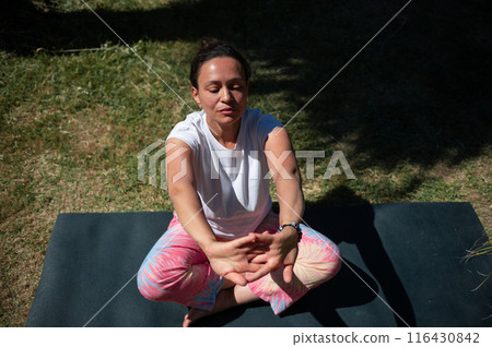 Woman meditating outdoors on a sunny day, practicing mindfulness and yoga 116430842