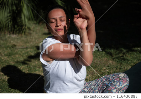 Woman practicing yoga outdoors in a peaceful garden setting Woman practicing yoga outdoors in a peaceful garden setting 116430885