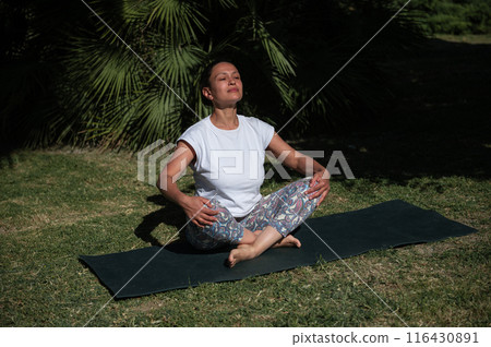 Woman practicing yoga in sunlight meditation outdoors in nature for relaxation and mindfulness 116430891