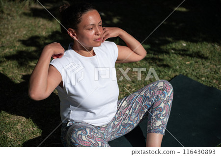 Woman practicing yoga outdoors on a sunny day, enjoying nature and relaxation 116430893