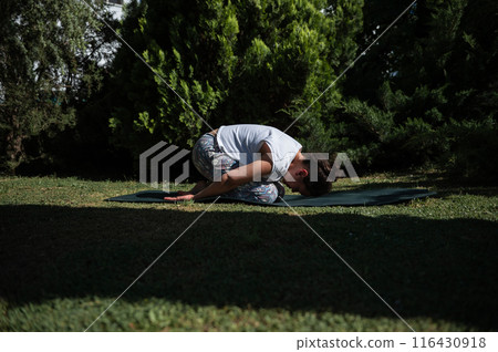 Woman practicing yoga in child's pose outdoors in a serene garden 116430918