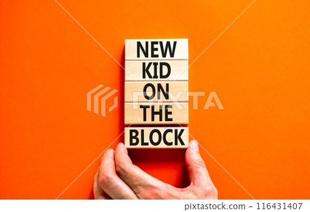 New kid on the block symbol. Concept words New kid on the block on wooden blocks. Businessman hand. Beautiful orange table orange background. Business and new kid on the block concept. Copy space. 116431407