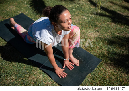 Woman practicing yoga outdoors on a mat in sunlight. Stretching in a yoga pose, focusing on flexibility and mindfulness Woman practicing yoga outdoors on a mat in sunlight. Stretching in a yoga pose, focusing on flexibility and mindfulness 116431471