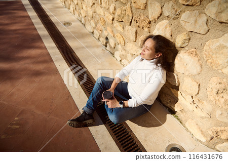 Woman relaxing outdoors with a cup of coffee in hand Woman relaxing outdoors with a cup of coffee in hand 116431676