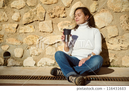 Woman relaxing outdoors with a coffee on a sunny day Woman relaxing outdoors with a coffee on a sunny day 116431683