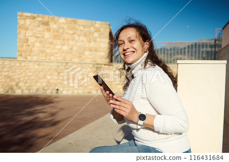 Happy woman using smartphone outdoors on a sunny day Happy woman using smartphone outdoors on a sunny day 116431684