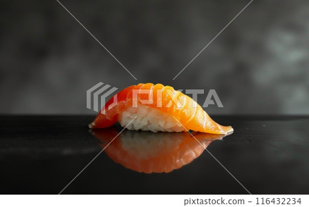 Lustrous salmon sushi piece delicately placed on a dark, reflective surface with scattered salt grains. 116432234