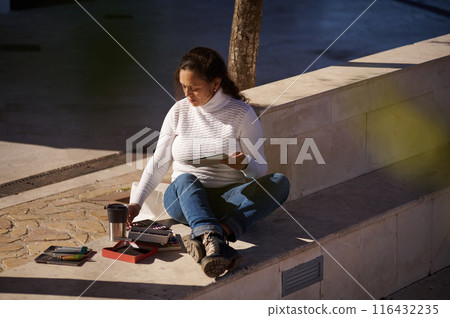 Woman relaxing outdoors while drawing on a tablet 116432235