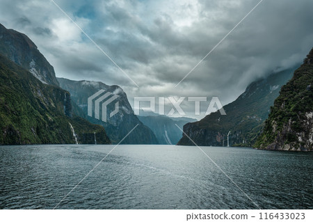 Cruise with majestic mountain and waterfall flowing in Milford Sound, New Zealand Cruise with majestic mountain and waterfall flowing in Milford Sound, New Zealand 116433023