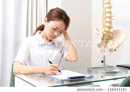Asian female medical worker worried about writing documents 116433181