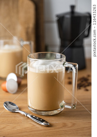 Two cups of freshly brewed aromatic coffee with milk on the kitchen table with a coffee pot Two cups of freshly brewed aromatic coffee with milk on the kitchen table with a coffee pot 116433263