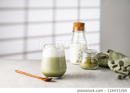 Green matcha latte in a glass on a gray background with morning shadows Green matcha latte in a glass on a gray background with morning shadows 116433269