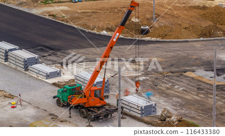 Installing concrete plates by crane at road construction site timelapse. Installing concrete plates by crane at road construction site timelapse. 116433380