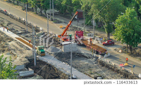 Orange construction telescopic mobile crane unloading tram rails from truck aerial timelapse. Orange construction telescopic mobile crane unloading tram rails from truck aerial timelapse. 116433613