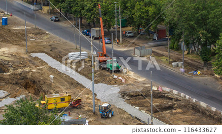 Unloading concrete plates from truck by crane at road construction site aerial timelapse. 116433627