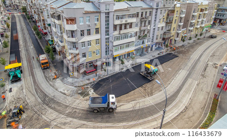 Asphalt paver, roller and truck on the road repair site during asphalting timelapse. Road construction equipment on a street Asphalt paver, roller and truck on the road repair site during asphalting timelapse. Road construction equipment on a street 116433679