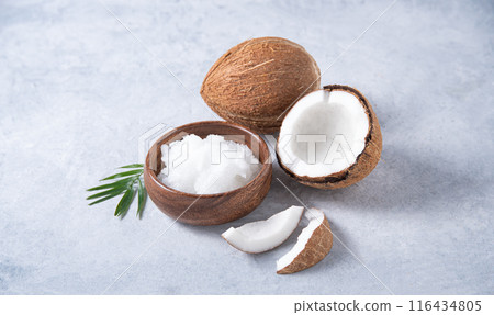 Healthy vegan coconut oil and half coconuts with slices on blue background. Copy space 116434805