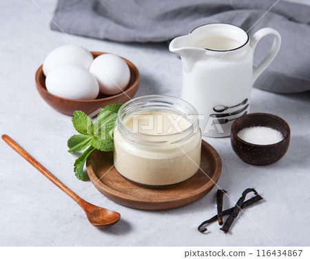 Delicious panna cotta or vanilla pudding in a jar on a light background with ingredients. Delicious panna cotta or vanilla pudding in a jar on a light background with ingredients. 116434867