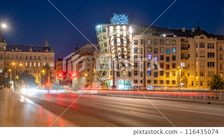 The Dancing House in Prague is illuminated by the city lights at dusk. The unique deconstructivist architecture stands out against the backdrop of traditional buildings. Light trails from passing cars The Dancing House in Prague is illuminated by the city lights at dusk. The unique deconstructivist architecture stands out against the backdrop of traditional buildings. Light trails from passing cars 116435074