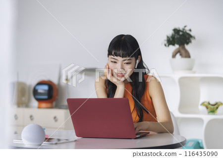 Young woman with earphones looking at laptop screen 116435090