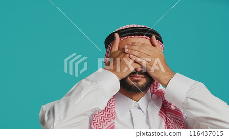 Adult showing three wise monkeys sign on camera, having muslim religious clothing and scarf. Young person covers his eyes, mouth and ears to present important metaphor symbol. Adult showing three wise monkeys sign on camera, having muslim religious clothing and scarf. Young person covers his eyes, mouth and ears to present important metaphor symbol. 116437015