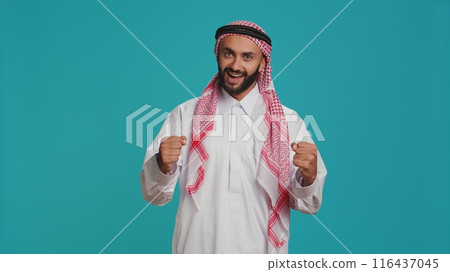Modern guy cheering and showing his support in front of camera, feeling optimistic and joyful about something. Middle eastern person being brave and giving strength with cheers. Modern guy cheering and showing his support in front of camera, feeling optimistic and joyful about something. Middle eastern person being brave and giving strength with cheers. 116437045