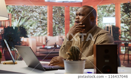 Freelancer managing startup projects and thinking about client needs from his home office, developing new growth strategy. Self employed analyst does telecommuting work on laptop. Camera B. 116437046