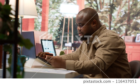Business owner makes a payment with his card for online shopping at his home, electronic banking to buy resources for his startup. Entrepreneur purchasing something on laptop. Camera A. Business owner makes a payment with his card for online shopping at his home, electronic banking to buy resources for his startup. Entrepreneur purchasing something on laptop. Camera A. 116437051