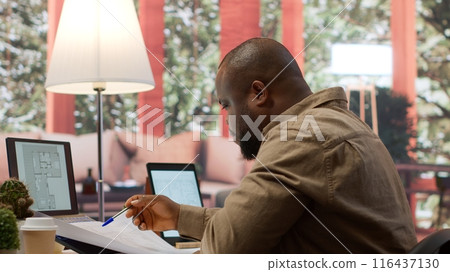Businessman analyzing architecture blueprints for new office space layout, looking to relocate startup. Entrepreneur conducts an office hunt, business development and strategy planning. Camera A. Businessman analyzing architecture blueprints for new office space layout, looking to relocate startup. Entrepreneur conducts an office hunt, business development and strategy planning. Camera A. 116437130