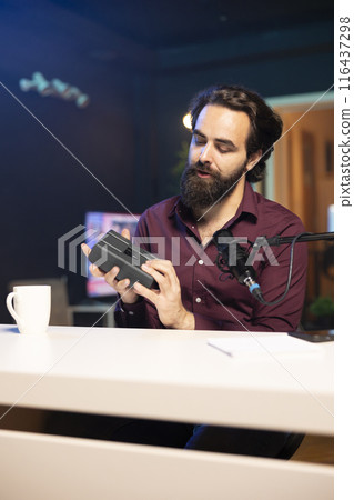 Tech content creator filming technology review of newly released V mount battery, analyzing it before giving opinion on specifications to audience. Media star showing charging device to subscribers 116437298