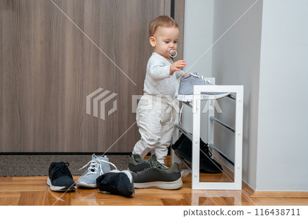 A child throws adults' shoes from a stand at the entrance. Pranks and antics 116438711