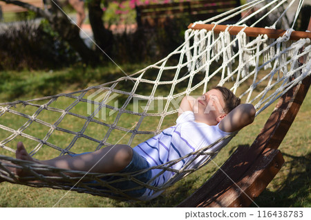 Happy teenage boy smiling lying on rope hammock 116438783