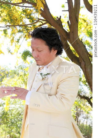 新娘穿著婚紗和新郎穿著燕尾服在盛開的含羞草樹下拍攝婚禮照片 116439211