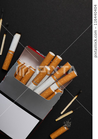 A pack of cigarettes with matches on a dark background A pack of cigarettes with matches on a dark background 116440404