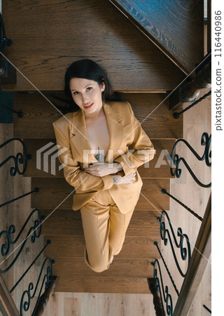 Woman in Yellow Suit Relaxing on Wooden Stairs 116440986