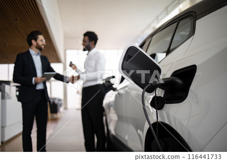 Dealer sells electric SUV to businessman in car dealership Dealer sells electric SUV to businessman in car dealership 116441733