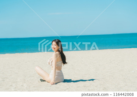 穿著泳衣的年輕女子坐在沙灘上 116442008