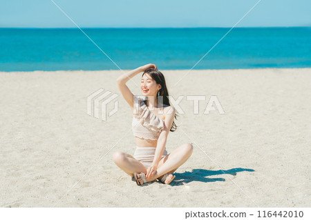 Young woman in swimsuit sitting on sandy beach Young woman in swimsuit sitting on sandy beach 116442010