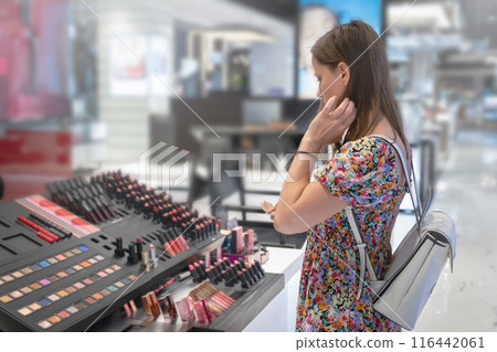 Woman shopping lipsticks for cosmetics in trendy store, exploring different products in fashionable setting 116442061