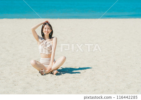 穿著泳衣的年輕女子坐在沙灘上 116442285