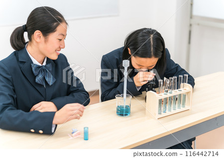 國中女孩在科學實驗中透過顯微鏡觀察 國中女孩在科學實驗中透過顯微鏡觀察 116442714