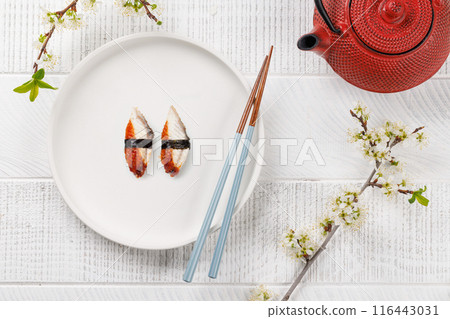 Eel sushi adorned with cherry blossom branch and chopsticks, epitomizing Japanese food culture 116443031