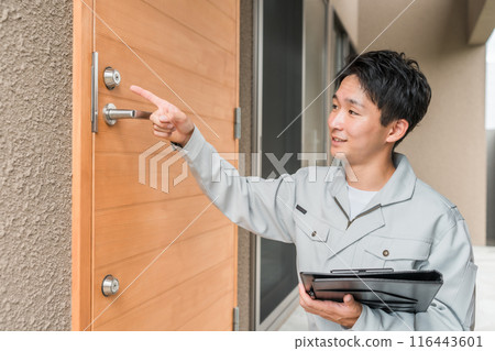 A male worker from a construction company or house manufacturer checking the front door 116443601