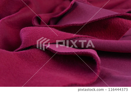A piece of fabric lies in waves. layers of French terry pink amaranth textile. 116444373